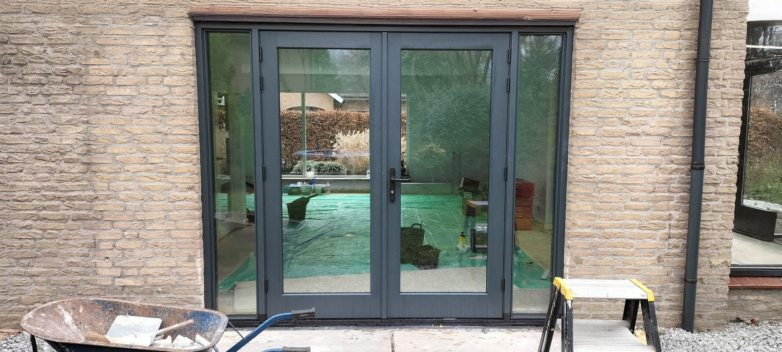 Nowoczesne grafitowe drzwi tarasowe z przeszkleniami zainstalowane w domu murowanym na terenie Holandii – profesjonalny montaż stolarki okiennej.