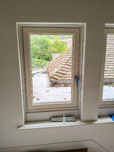 Widok od wewnątrz na zamontowane okno z widocznymi materiałami uszczelniającymi na parapecie